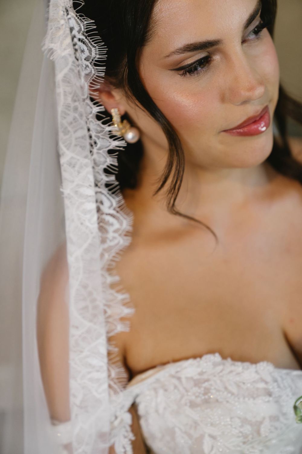 Bride in a lace mantilla veil with glowing skin, winged liner and glossy lips