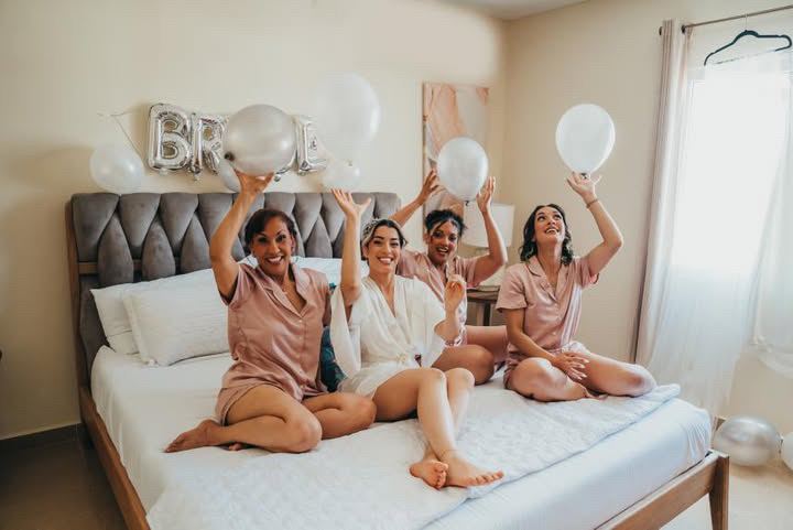 Bride and bridesmaids in robes celebrating with balloons