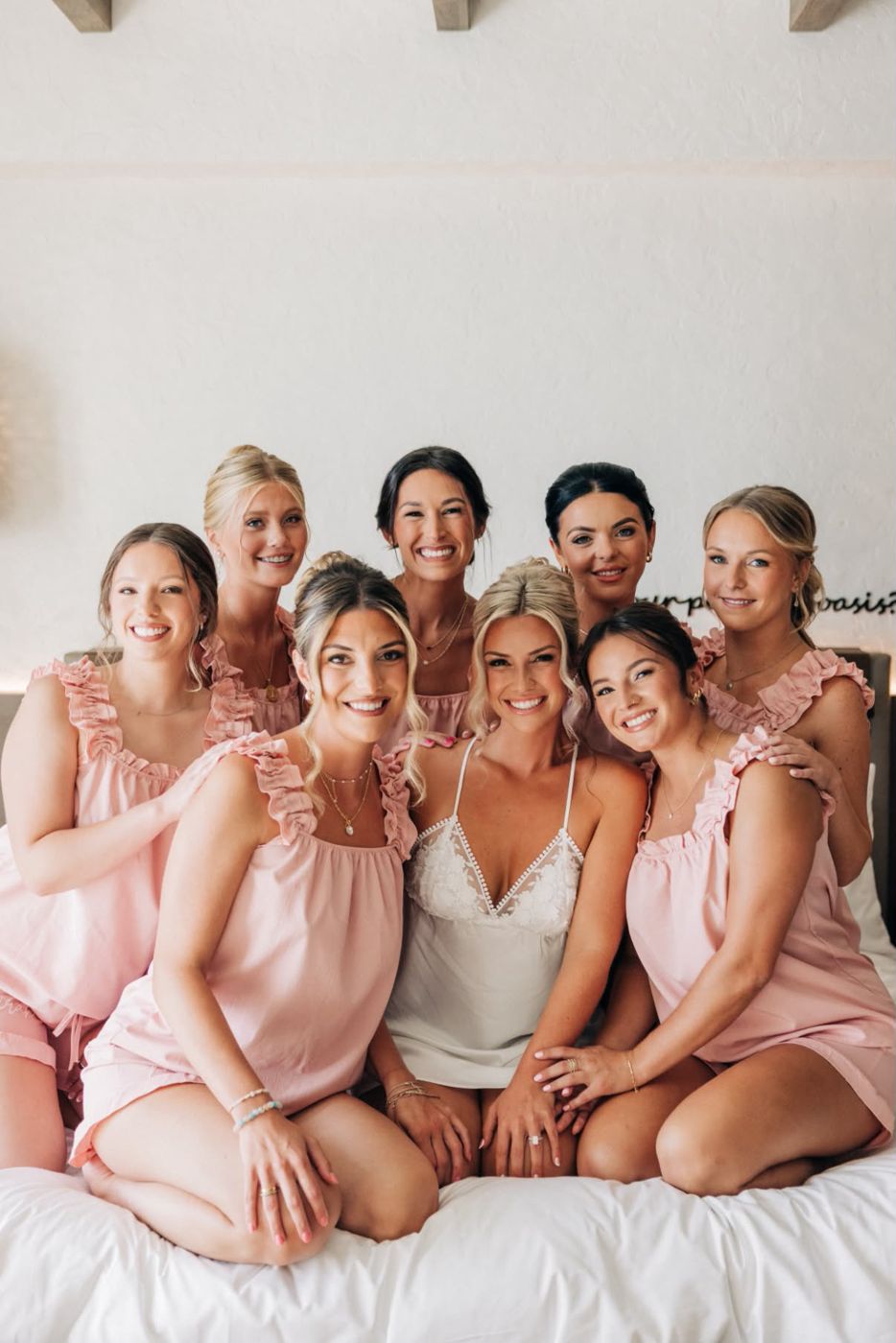 Bride and seven bridesmaids in matching pink pajamas smiling together