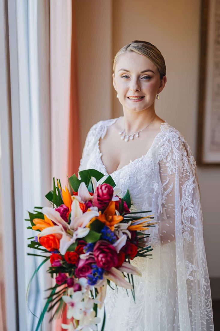 Bride by a window holding a tropical bouquet